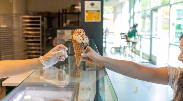 A worker hands a student an ice cream cone from Scoops at the HUB.