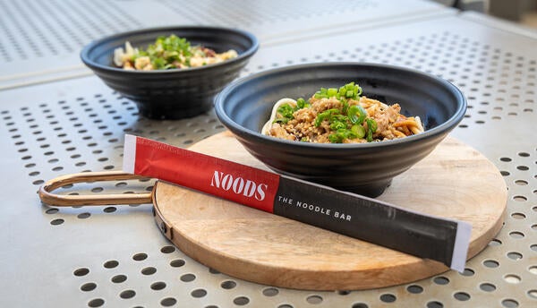 two bowls of noodles with noods branded chopsticks