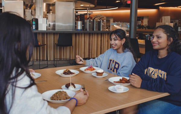 three students eating indoors at Glasgow smiling