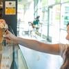 A scoops employee hands an ice cream cone to a student.