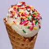 A scoop of vanilla ice cream in a cone with sprinkles on top from Scoops.