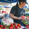 A student worker places fresh pieces of watermelon on a table.