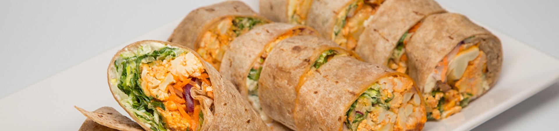 Pre-cut chicken wraps on a white platter.